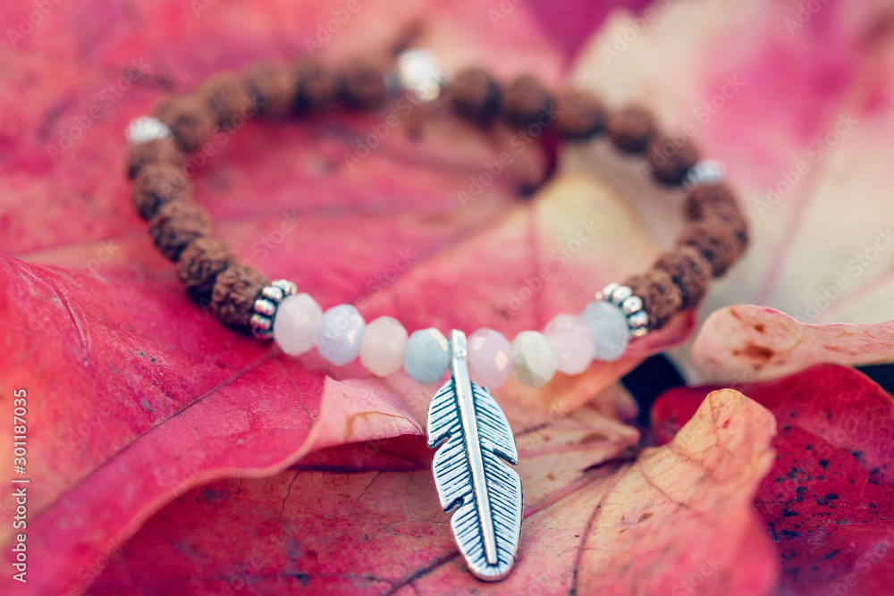 Metal feather pendant mineral stone bracelet on autumn background