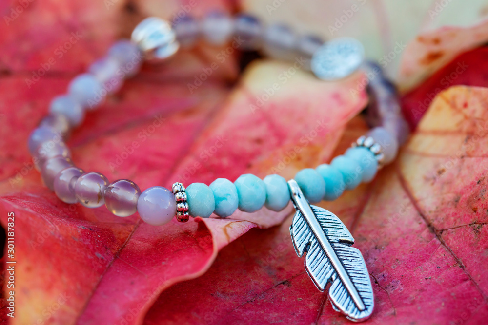 Metal feather pendant mineral stone bracelet on autumn background