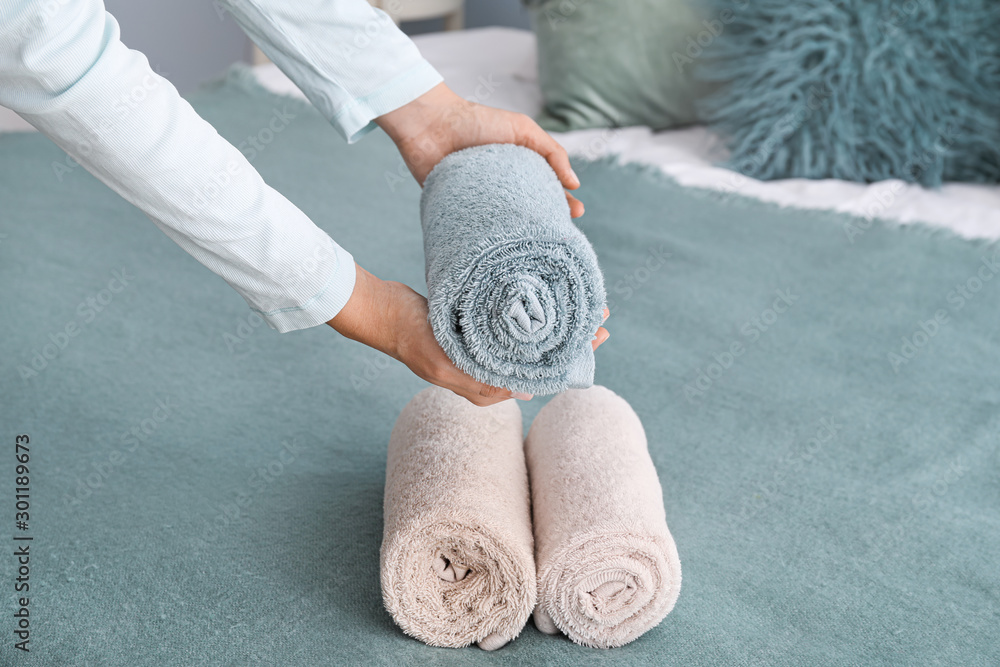 Woman putting soft towels on bed