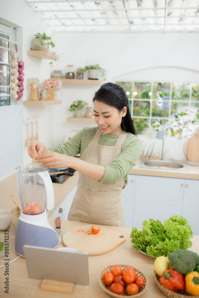 年轻女士站在厨房里用平板电脑烹饪蔬菜沙拉的画面