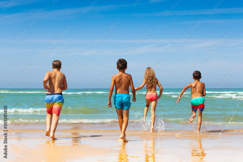 Back view of kids walking to the sea from beach