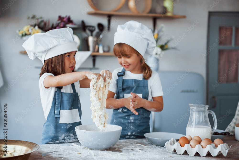 Family kids in white chef uniform preparing food on the kitchen