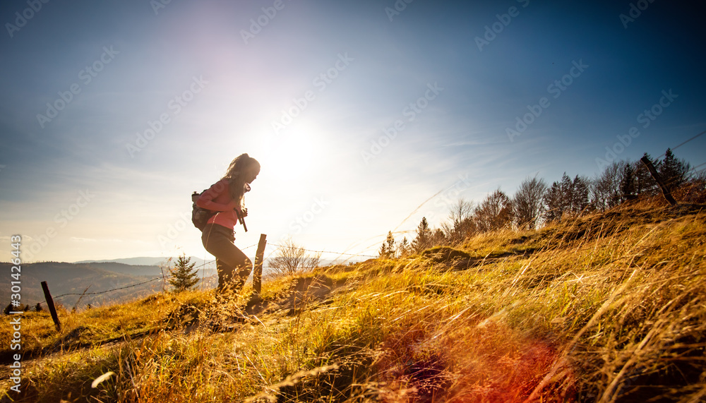 徒步旅行的年轻女子背着背包在群山景观背景下登上山顶