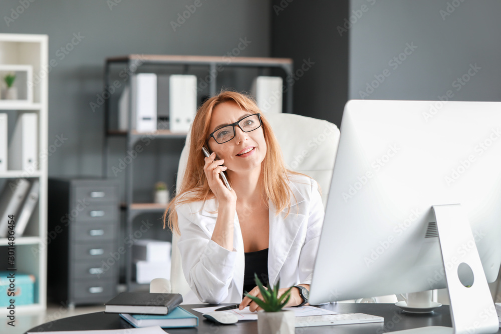 Portrait of mature businesswoman talking by phone in office