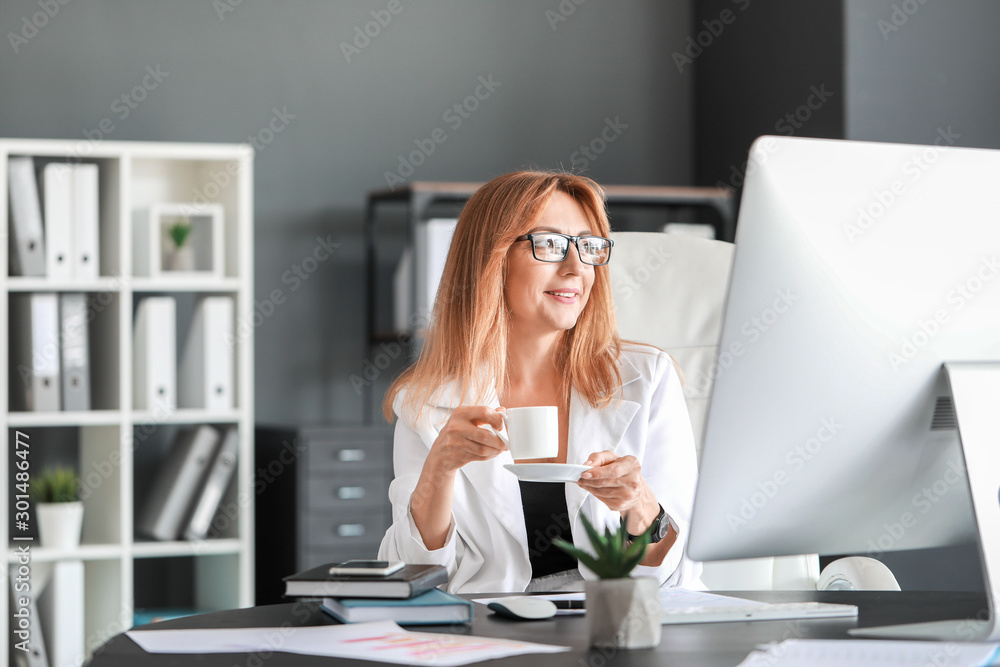 Portrait of mature businesswoman drinking coffee in office