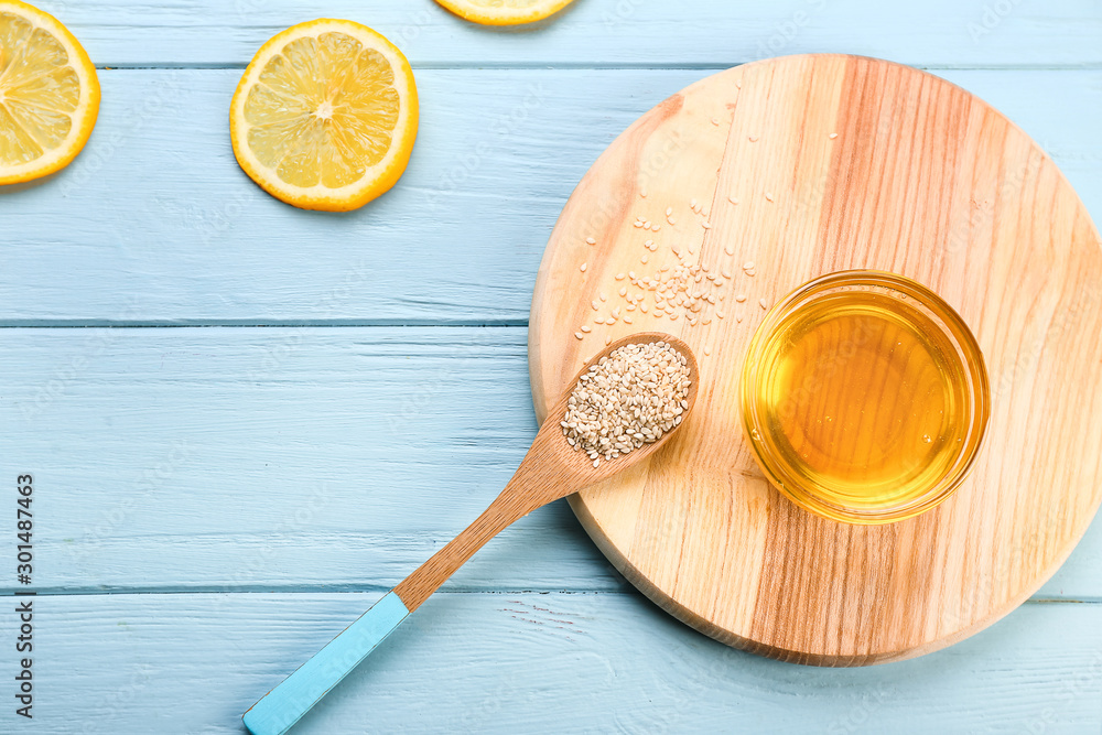 Bowl with honey, lemon and spoon with sesame on wooden table