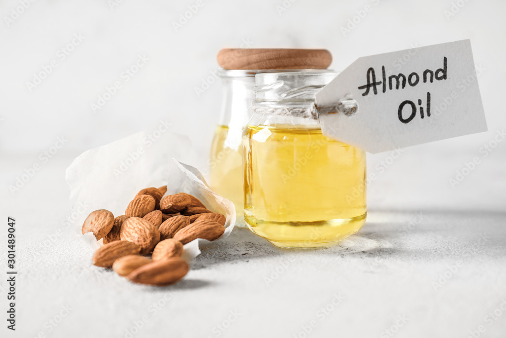 Jars with almond oil on white background