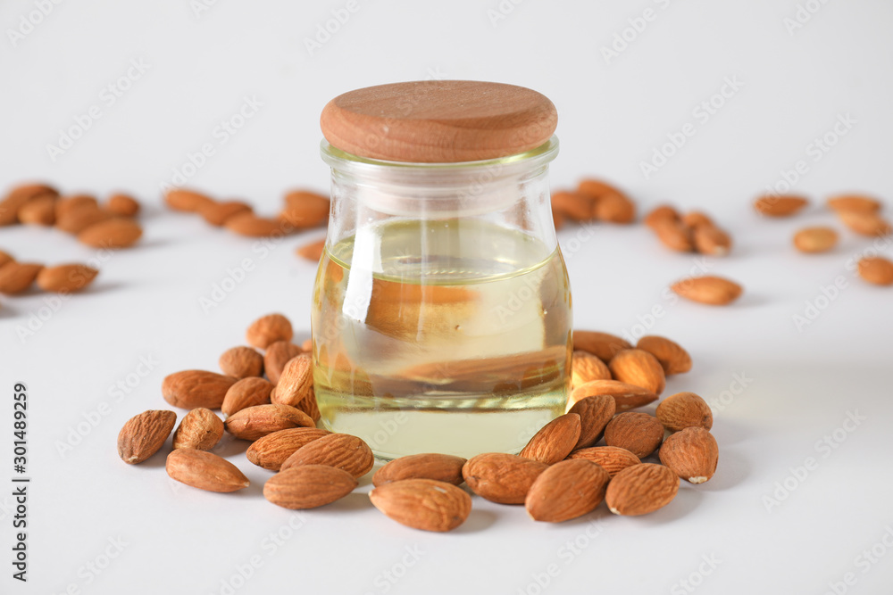 Tasty almond oil with nuts on white background