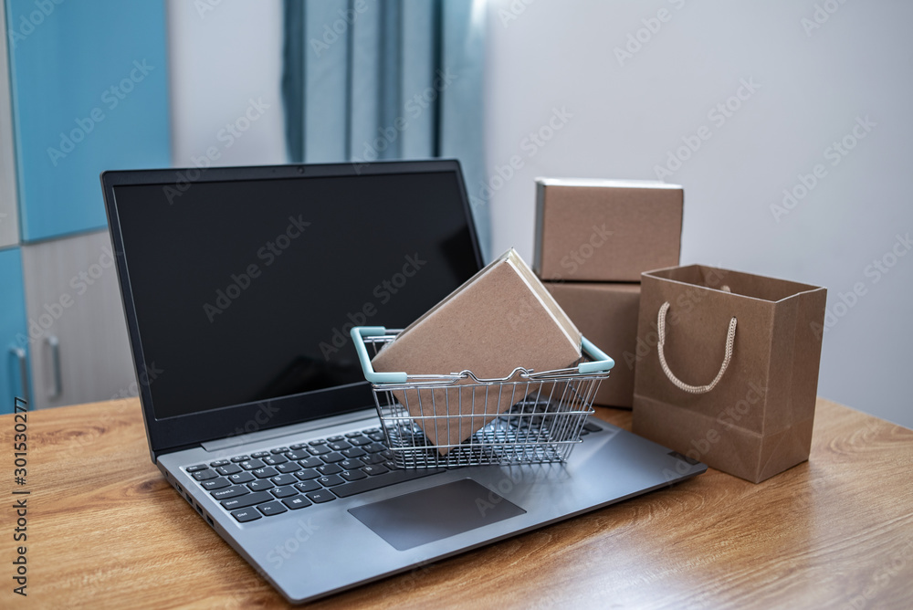 Laptop and online shopping cartons on the desk, shopping basket background material