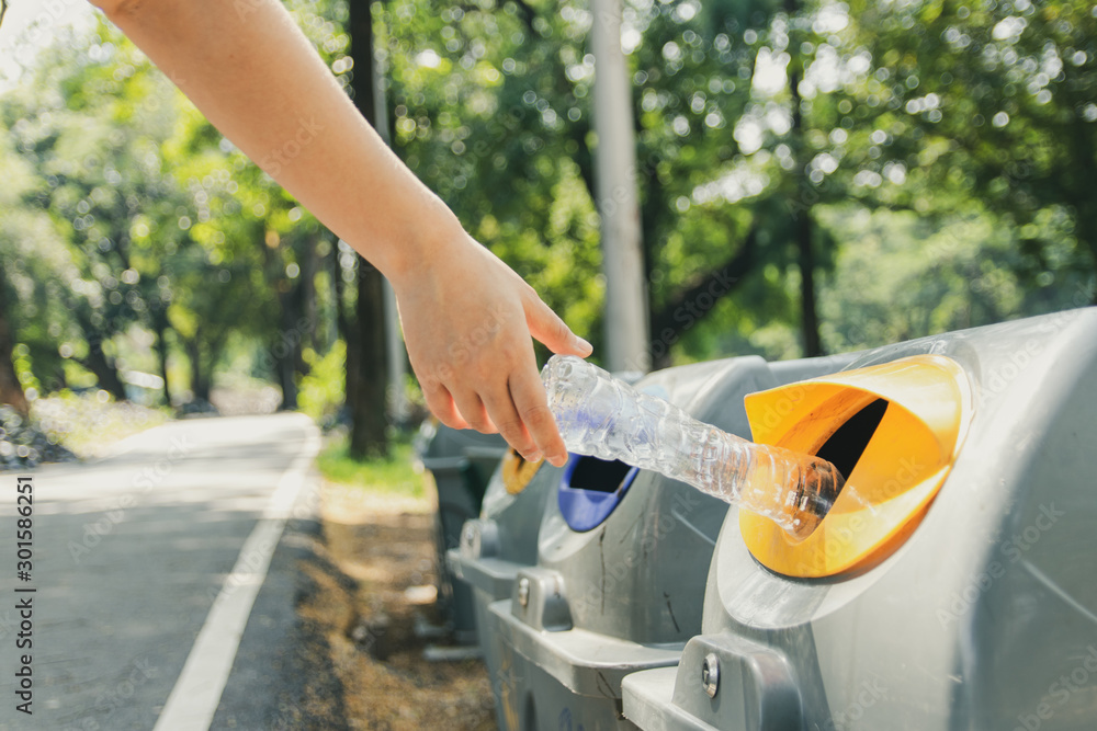 Woman hands throw plastic bottles into the trash.