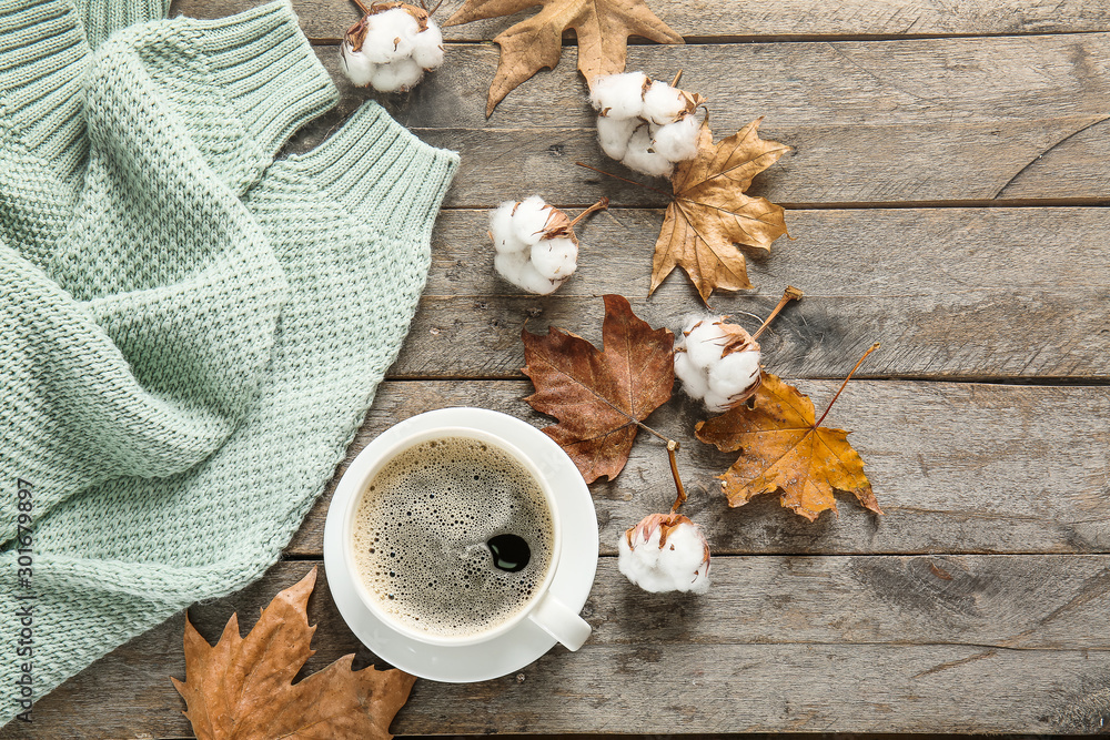 Warm sweater, cup of coffee, autumn leaves and cotton flowers on wooden background