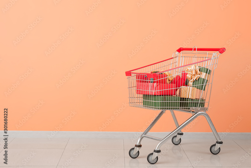 Shopping cart with gifts near color wall