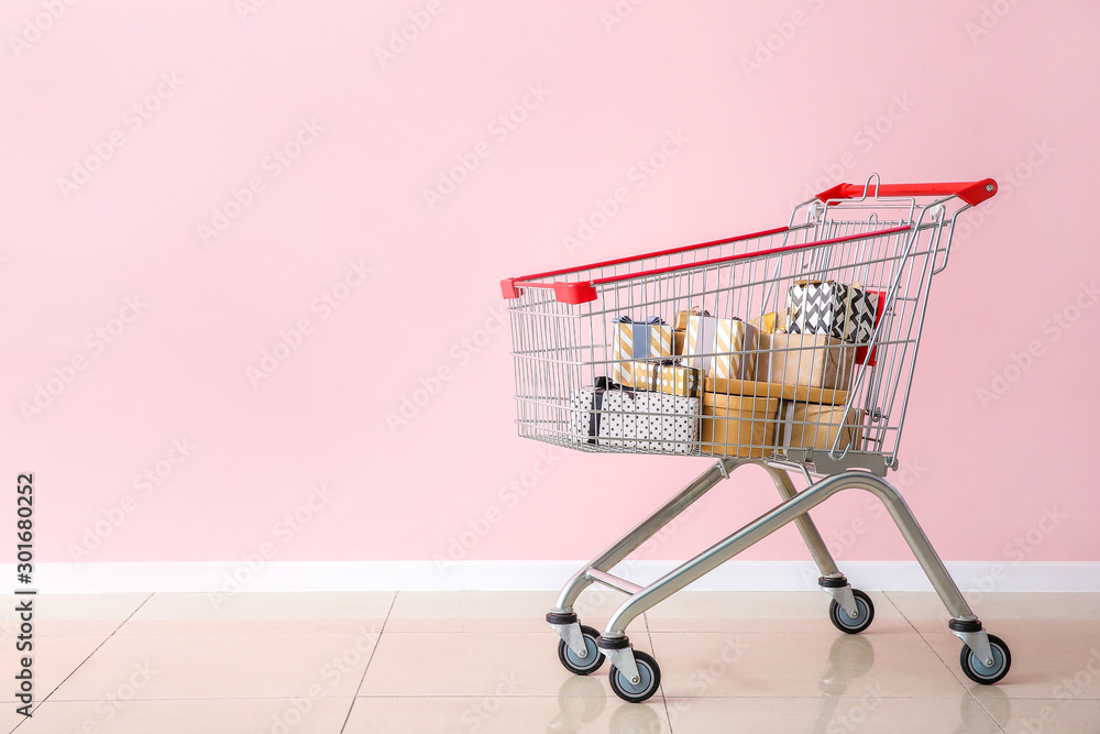 Shopping cart with gifts near color wall