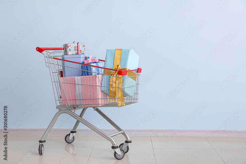 Shopping cart with gifts near color wall