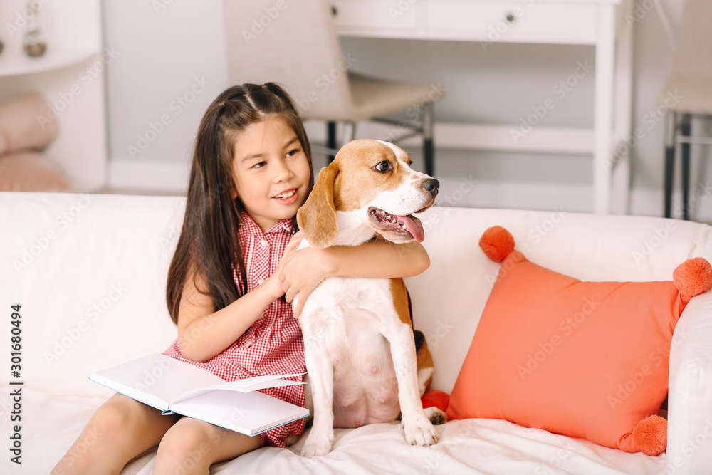 亚洲小女孩带着可爱的小猎犬在家看书