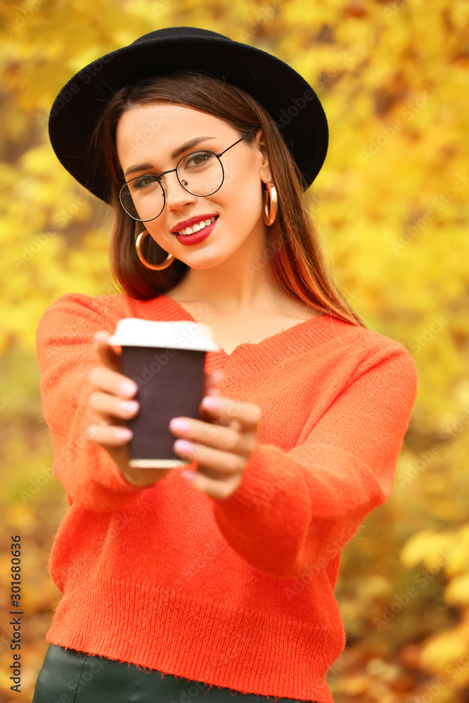 Stylish young woman with cup of coffee on autumn day