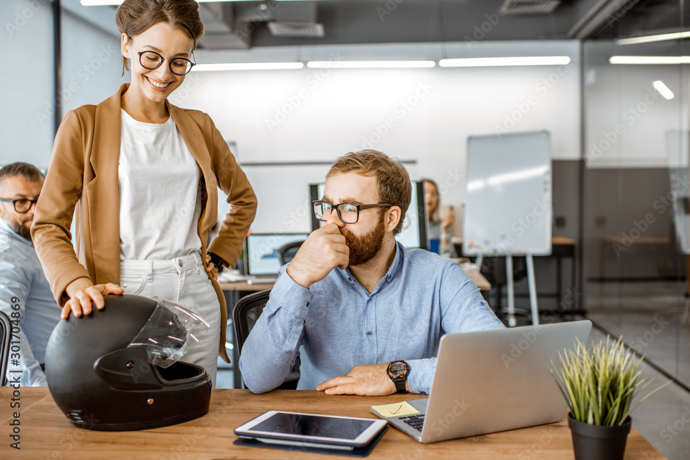 Two young colleagues talking at the working place, solving some working moments in the busy office o