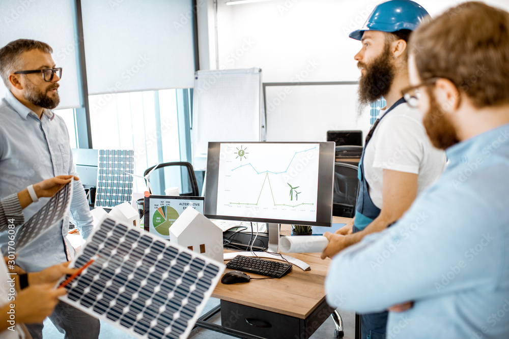 Group of alternative energy engineers discussing a project with a worker during a meeting in the off