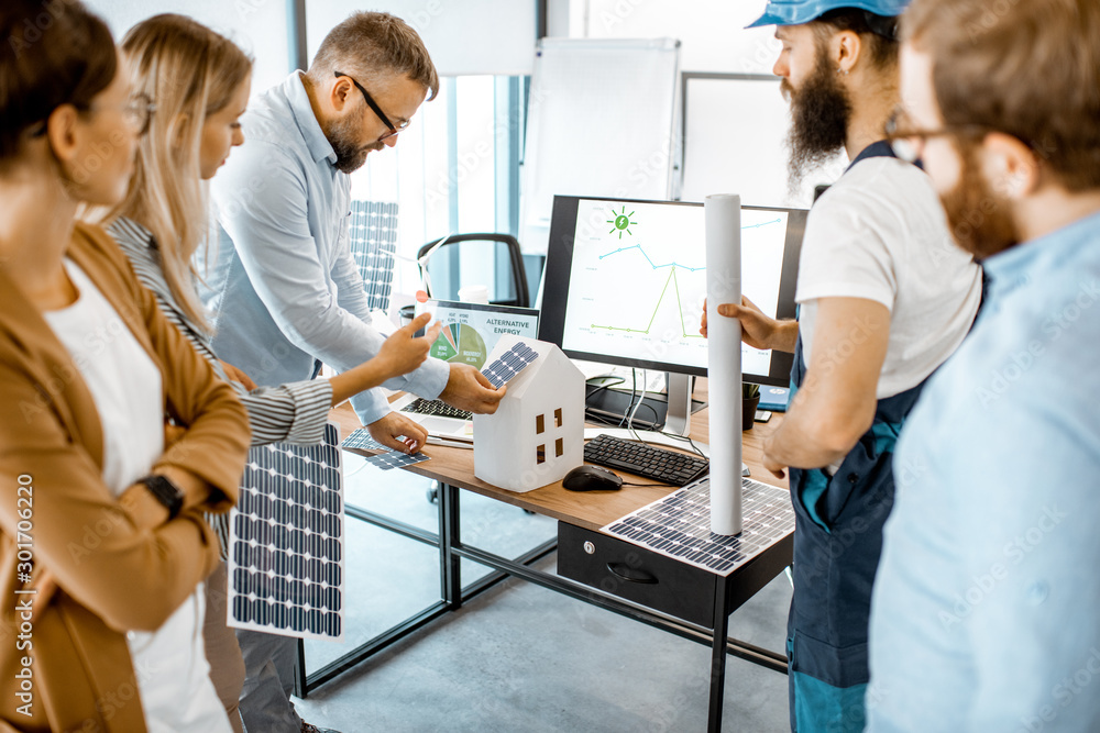 Group of alternative energy engineers discussing a project with a worker during a meeting in the off