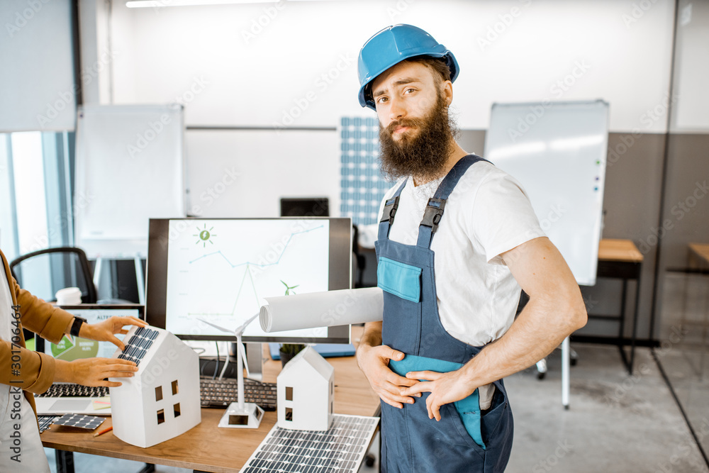 Portrait of a bearded worker in workwear and protective helmet standing in the alternative energy de