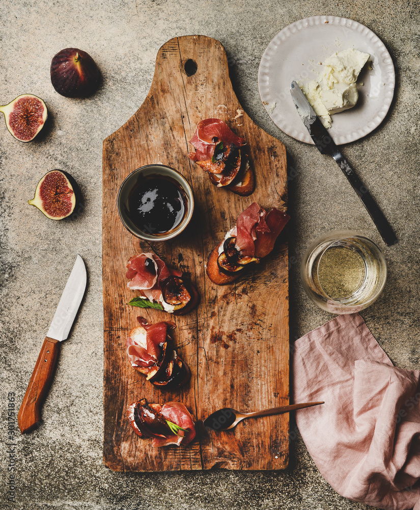 Party or catering food. Flat-lay of crostini with prosciutto, goat cheese and grilled figs on wooden