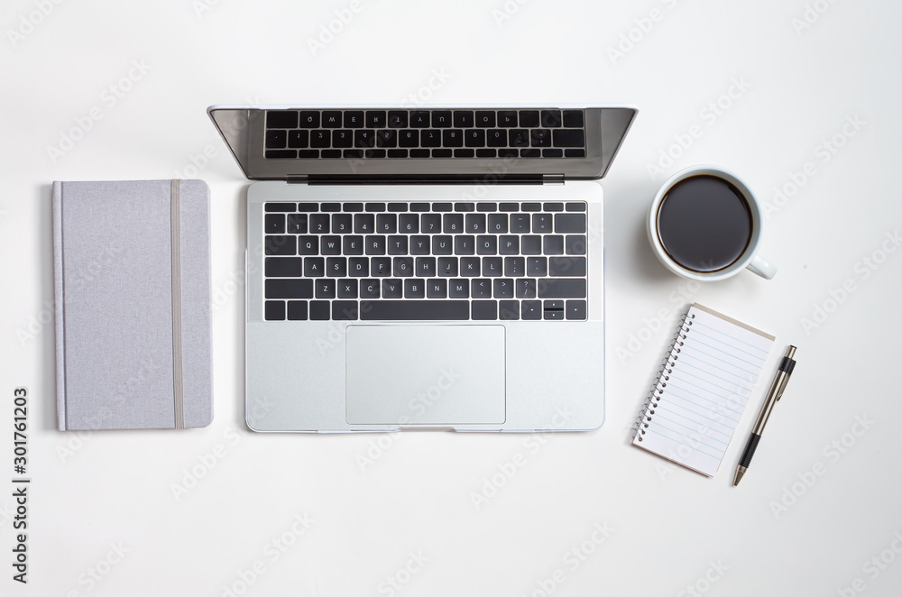 Laptop computer with coffee, notepad and journal on a table