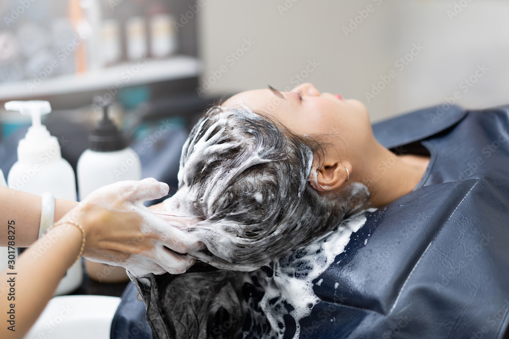 Beautician is washing her hair, is a beautiful woman. In a beauty salon