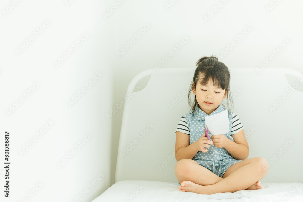 Portrait of a little asian girl cutting a paper in activities on DIY class at Home School.Scissors c