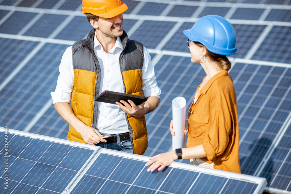 Two engineers or architects examining the construction of a solar power plant, standing with digital