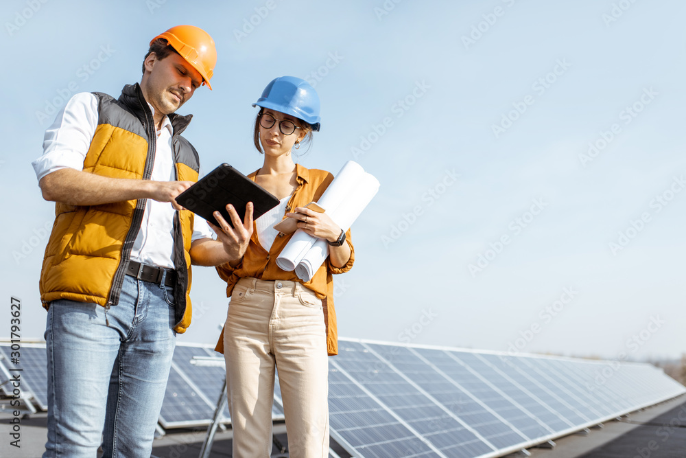 Two engineers or architects examining solar power plant with a digital tablet. Solar station develop