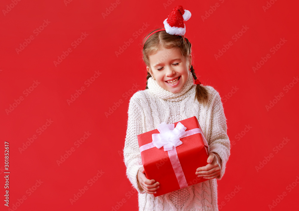 happy funny child girl    with Christmas gift on red   background.