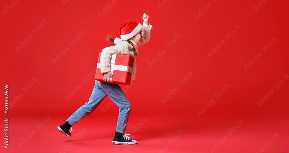 happy funny child girl    with Christmas gift on red   background