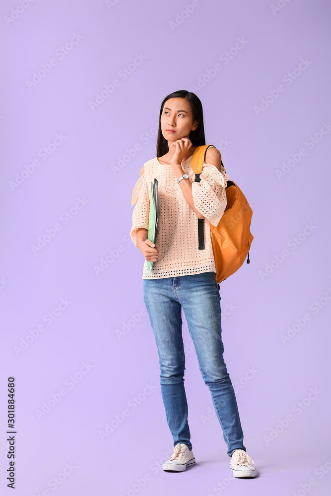 Portrait of thoughtful Asian student on color background