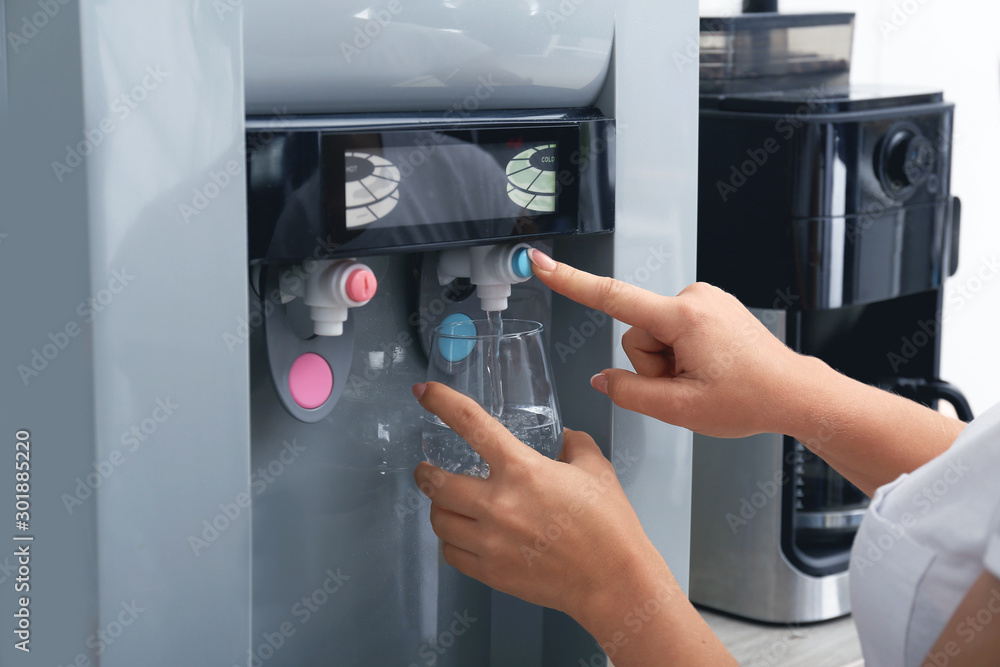 Woman pouring water from cooler into glass, closeup