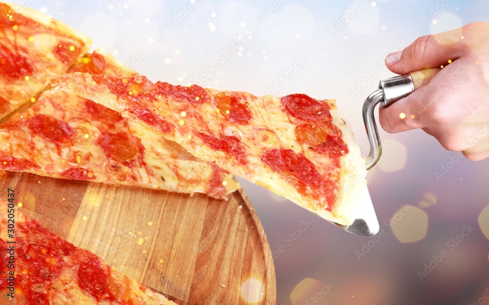 A slice of pizza on a spatula on the background of the main dish