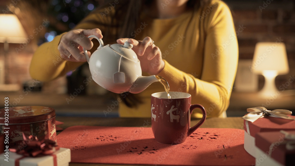 女人在节日杯子里倒热茶