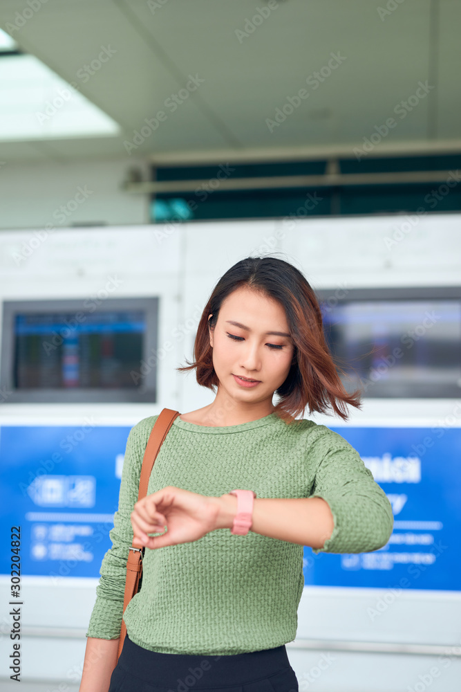 Beautiful asian woman looks at wristwatch for checking the time.