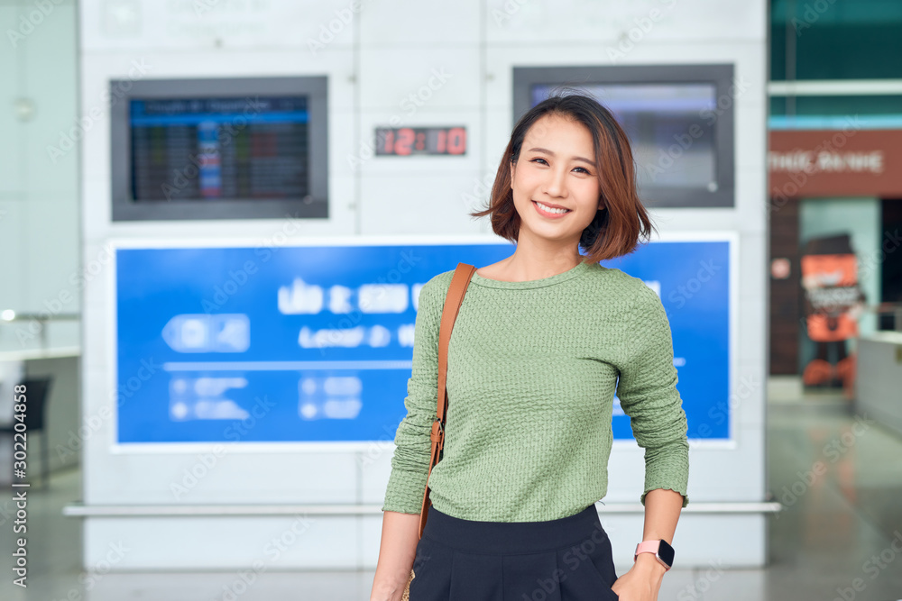 Travel. Young woman goes at airport at window with suitcase waiting for plane