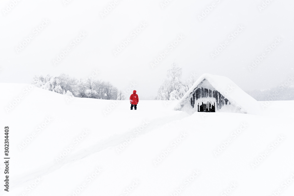 极简主义的冬季景观，木屋和雪山中的游客。多云的天气，土地