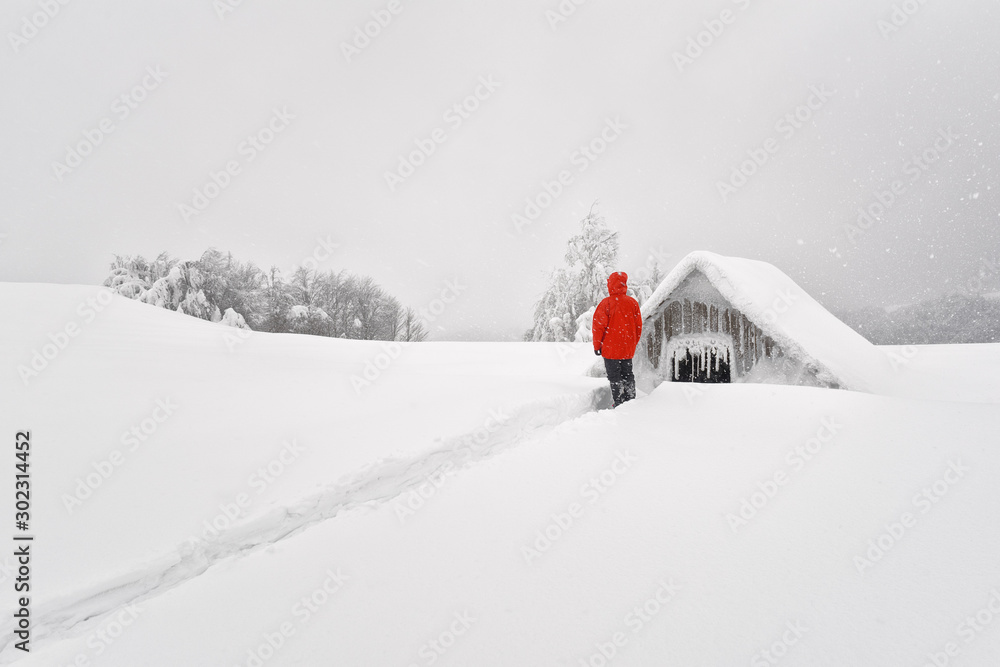 带木屋的极简主义冬季景观和雪山中的游客。多云的天气，土地