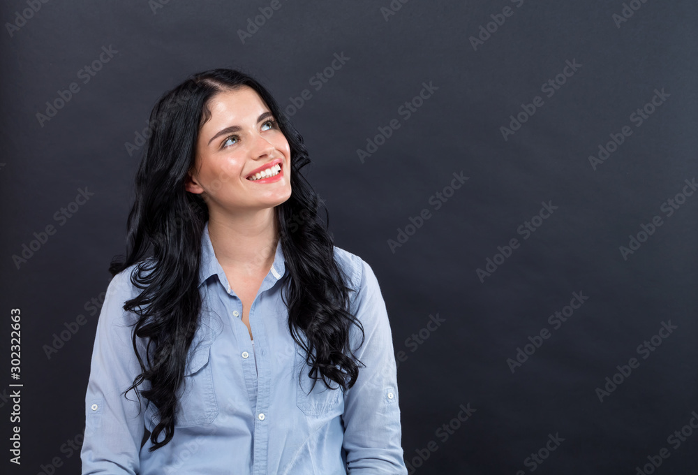 Young woman in a thoughtful pose on a black background