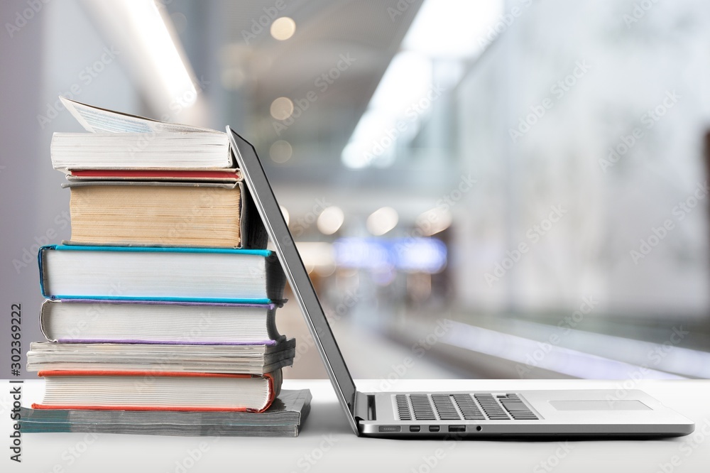 Stack of books with laptop on table