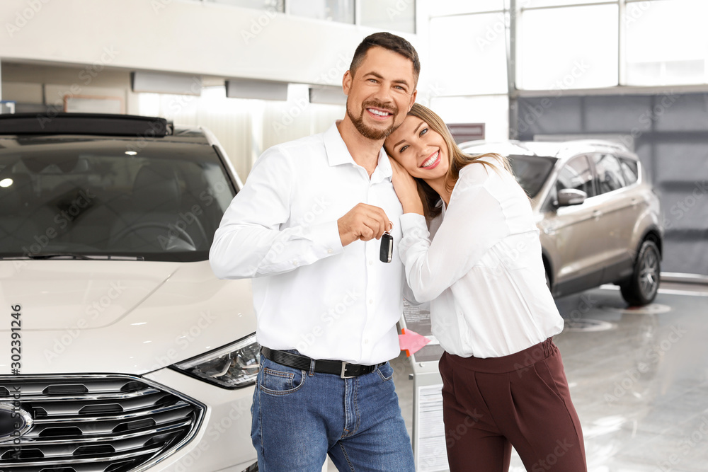 Happy couple after buying new car in salon