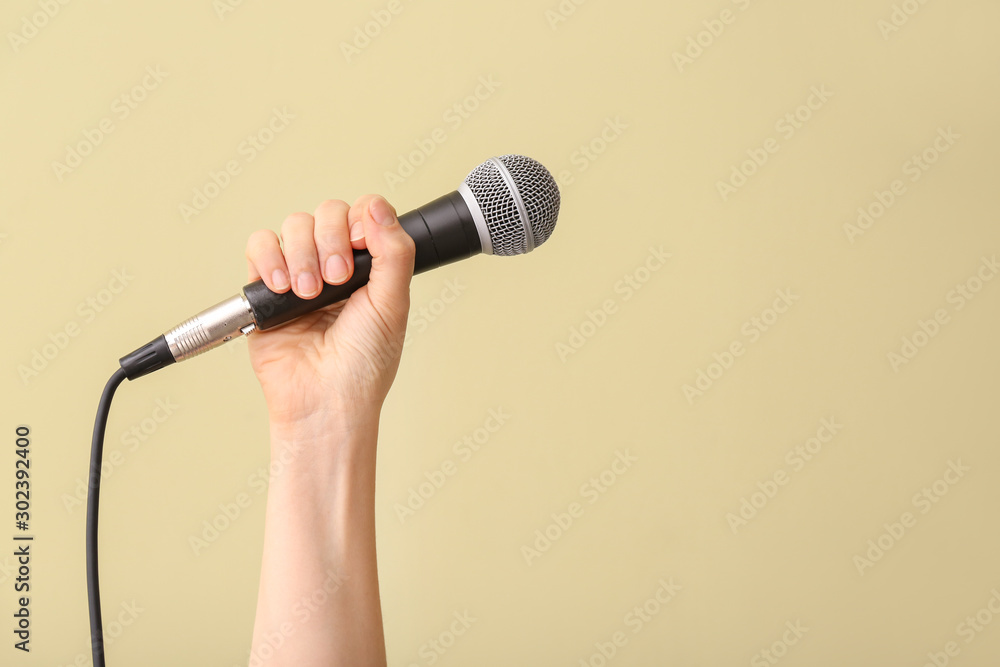 Female hand with microphone on color background