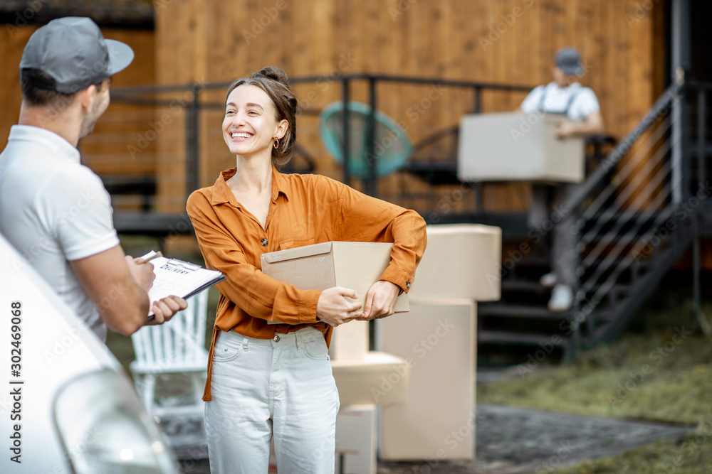 Portrait of a happy client with a male courier delivering goods by vehicle to a woman home, workman 