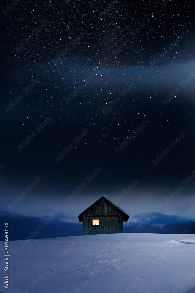 Blockhaus mit Leuchtendem Fenster im Winter bei Dämmerung