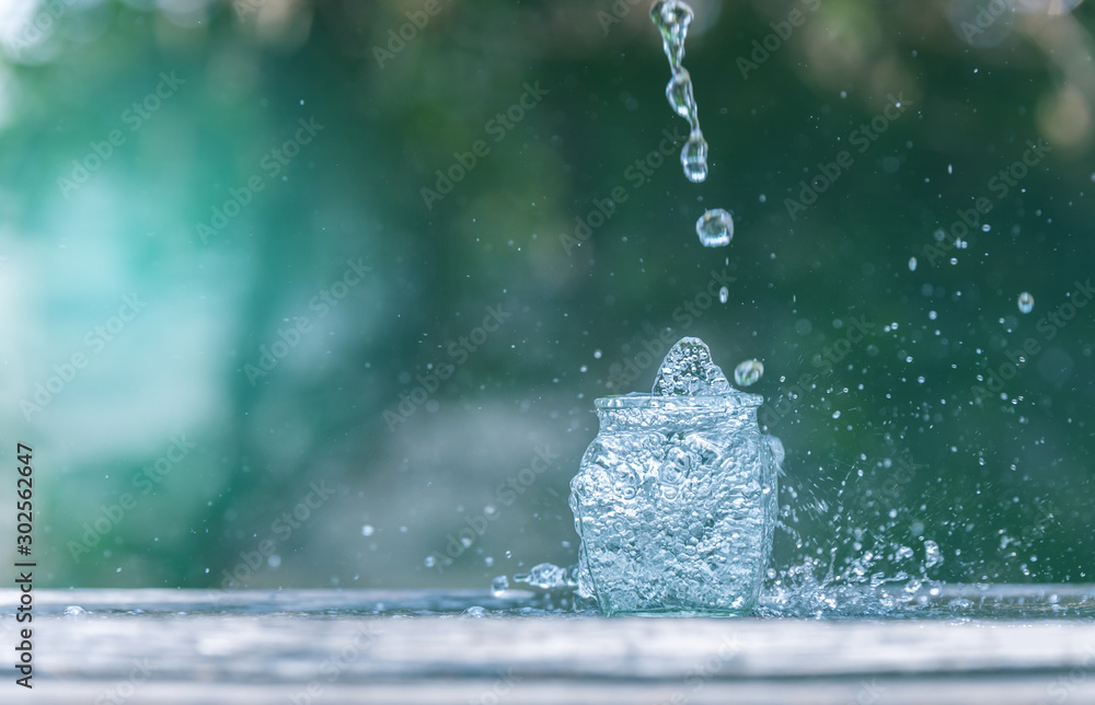 Water splash in glass Select focus blurred background.Drink water pouring in to glass over sunlight 