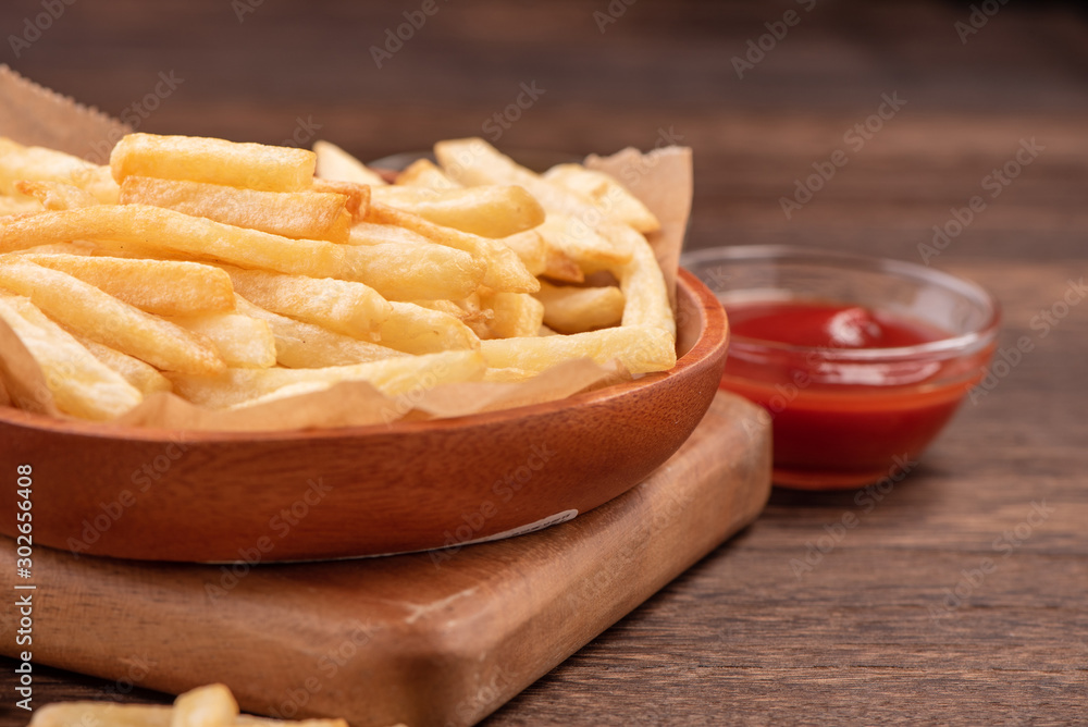 Golden yummy deep French fries on kraft baking sheet paper and serving tray to eat with ketchup and 