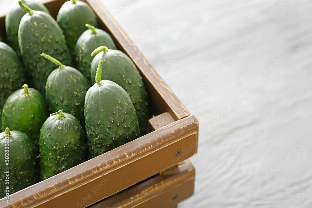 Fresh green cucumbers in box on table