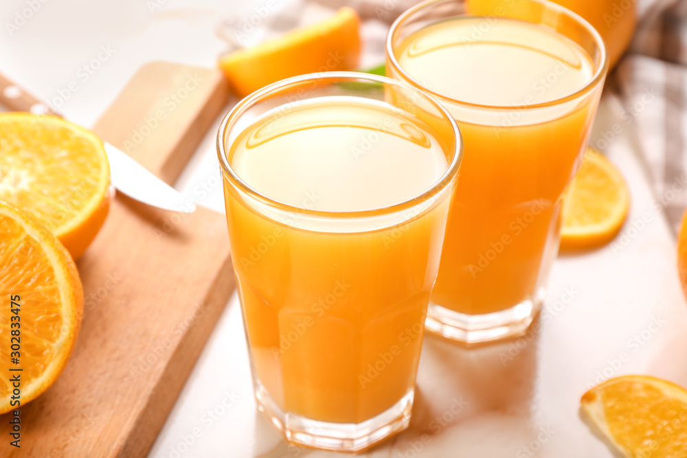 Glasses of fresh orange juice on light table